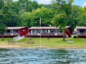 a red house with a picnic table next to the water at Happy Hollow Resort in Blue Eye