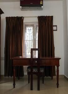 a piano and a chair in front of a window at Casa Linda in Cochin