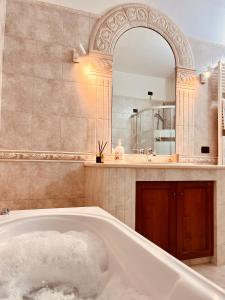 ein Badezimmer mit Badewanne und großem Spiegel in der Unterkunft House in Cave in Massafra