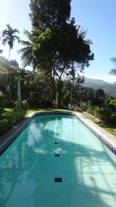 a large blue swimming pool with trees in the background at Strathisla Tea Estate Bungalow in Matale