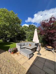 un patio con sofá, mesa y sombrilla en Lodge near Bath for relaxing getaway with Hot tub, en Chittoe