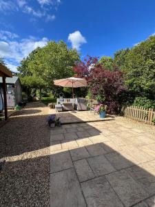 un patio con una mesa y una sombrilla en Lodge near Bath for relaxing getaway with Hot tub, en Chittoe