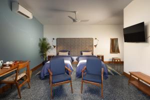 a bedroom with a bed and two blue chairs at Jaali Blue in Canacona