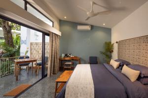 a bedroom with a bed and a balcony with a table at Jaali Blue in Canacona