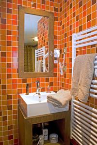 an orange tiled bathroom with a sink and a mirror at Résidence Montana Caron by Village Montana in Val Thorens