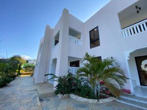 a white building with a palm tree in the courtyard at Vipingo Luxury Villa in Kilifi +1 photo