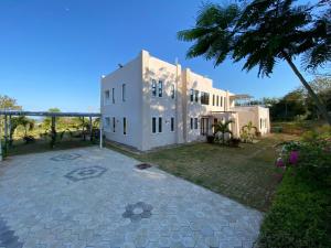 a large white house with a palm tree in front of it at Vipingo Luxury Villa in Kilifi