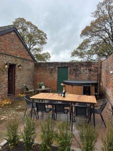 Courtyard House- Luxury Holiday House with floodlit Tennis court في نورثاليرتون: فناء في الهواء الطلق مع طاولة وكراسي خشبية +49 صورة