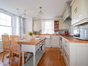 a kitchen with white cabinets and a wooden table at Tradewinds in Newquay
