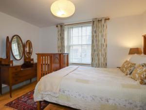 a bedroom with a bed and a dresser and a window at Tradewinds in Newquay