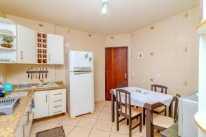 a kitchen with a table and a white refrigerator at Beira Mar e Frente Lagoa de Barra Velha 4 Quartos in Barra Velha