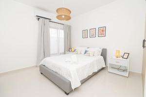 a white bedroom with a white bed and a window at Cozy 1-BR Apartment in Bayahibe in San Rafael del Yuma +33 photos