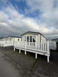 a house with a porch and a white fence at Poppy Lodge LE 17 Ocean's Edge Park in Morecambe