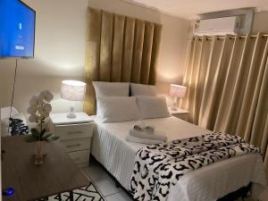 een slaapkamer met een bed met witte lakens en een televisie bij Tranquil Retreat in Durban +4 foto's
