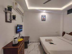 a bedroom with a bed and a desk and a tv at The Hotel Eden Beach in Puducherry