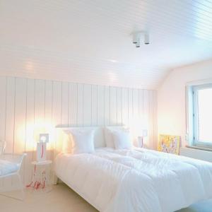 a white bedroom with a white bed and a window at BEEEP Stay in Hasselt