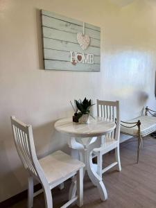 a white table and chairs with a heart sign on the wall at The Cozy Rustic in General Trias
