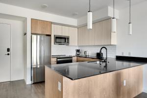 Il comprend une cuisine équipée d'un comptoir noir et d'un réfrigérateur. dans l'établissement Blueground New Tacoma balcony nr Museum SEA-957, à Tacoma