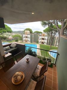 a balcony with a wooden table and chairs and a pool at Apartamento Rocio en Calella in Calella de Palafrugell
