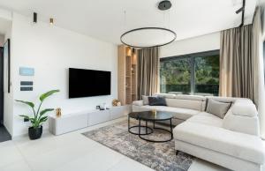 a white living room with a white couch and a tv at Luxury Villa Helena, with heated pool in Makarska