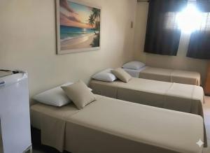 a room with three beds and a picture of a beach at Hotel Porto Real in Pôrto Real