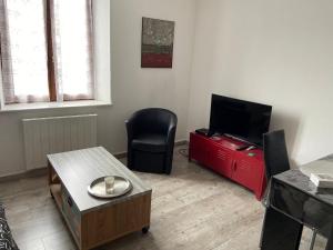 a living room with a television and a chair at Aux Portes de Brisach in Sélestat