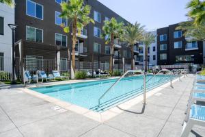 ein Swimmingpool mit Palmen und einem Gebäude in der Unterkunft Blueground East Industrial pool nr Central Park SFO-2045 in Warm Springs District