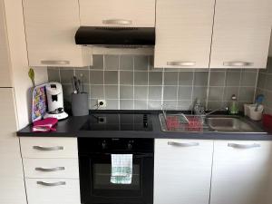 a kitchen with white cabinets and a black stove top oven at Aux Portes de Brisach in Sélestat