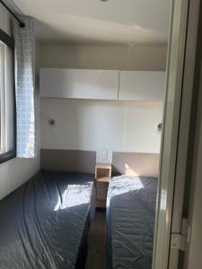 a small room with two beds and a window at Mobil-home 33 st jean de monts camping 5 étoiles in Saint-Jean-de-Monts