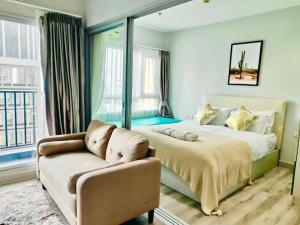 a bedroom with a bed and a couch and a window at Centric Sunset Beach in Pattaya Central
