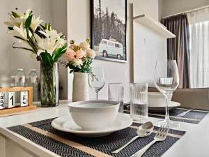 a table with a bowl and glasses and a vase with flowers at Centric Sunset Beach in Pattaya Central