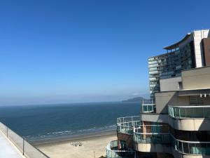 a building next to a beach with the ocean at Flats na praia com AC, piscina, sauna e academia! in Santos
