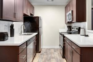 a kitchen with wooden cabinets and a stainless steel refrigerator at Blueground Campbell pool nr Campbell Park SFO-1998 in Campbell