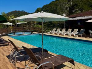 una mesa con sombrilla junto a la piscina en Estação Serramar, en Lumiar