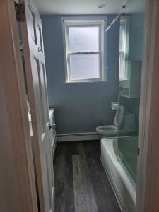 a bathroom with a shower and a toilet and a window at Cozy Getaway in Kearny