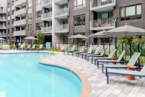 einem Pool mit Stühlen und Sonnenschirmen vor einem Gebäude in der Unterkunft Blueground East Industrial pool nr Central Park SFO-2080 in Warm Springs District