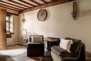 a living room with two chairs and a clock on the wall at Homestead - Cosy Cotswolds Cottage with Hot Tub in South Cerney +23 photos