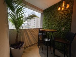 a green wall with a table and a plant at Tupis Flats 1401 in Belo Horizonte