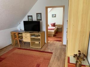 ein Wohnzimmer mit einem TV und einem Schreibtisch mit einem Bett in der Unterkunft Ferienhaus HirschRudel - Ferienwohnung 4 in Lodmannshagen