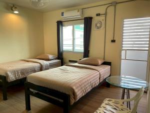 a room with two beds and a glass table at Banhor Residence in Chiang Mai