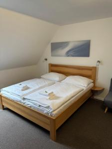 een slaapkamer met een groot bed met witte lakens bij Penzion Laskala in Tišnov