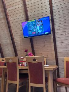a television on a wall above a table with chairs at A Frame la Iaz in Mărăcineni