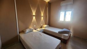 a small room with two beds and a window at Shapon Hotel - Hurghada in Hurghada