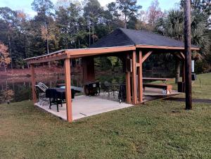 einen hölzernen Pavillon mit einem Tisch und einem Grill in der Unterkunft Cozy Cabin for Two by the Lake for a Peaceful Escape in Opelika, Alabama in Opelika