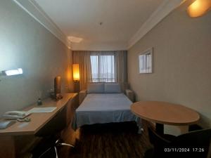 グアルーリョスにあるHotel Guarulhos Flat 902のベッドと机とテーブルがあるホテルの部屋