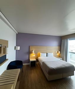 a hotel room with a large bed and a window at Apartamentos Luxuosos a Passos do Mar no Helbor Stay - Airbn Santos in Santos