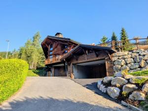 a log home with a garage and a stone wall at Chalet Camomille in Les Gets