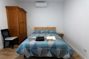 a bedroom with a bed with a blue comforter and a chair at El Salón de Arriba in El Real de San Vicente +45 photos