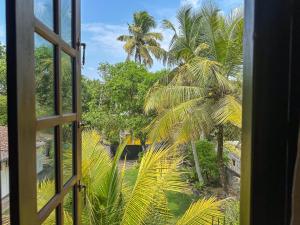 an open window looking out at a palm tree at Stay Happy at Chathurni Villa, Ahangama in Ahangama