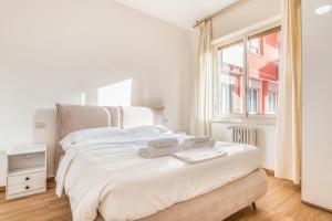 ein weißes Schlafzimmer mit einem großen Bett und einem Fenster in der Unterkunft Sesto Rondò Ospedale San Raffaele 4 Pax Wi-Fi in Sesto San Giovanni